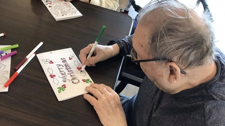 An elderly man colouring Christmas cards at Sagebrush